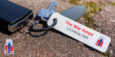 A set of keys with a War Amps key tag attached laying on the ground.